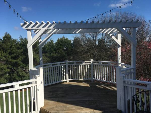 a white pergola covering a corner of a deck