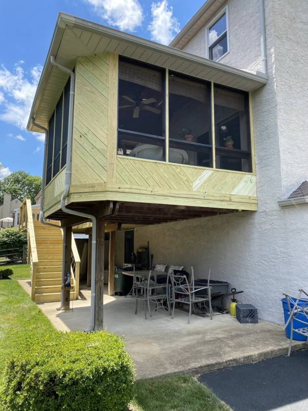 a brand new sunroom next to a deck at the back of a home